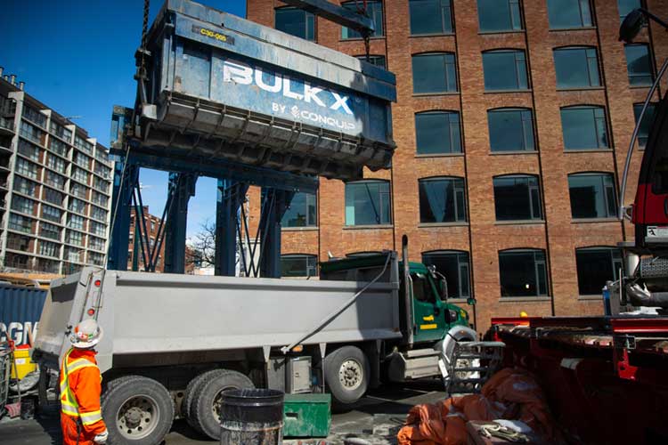 Conquip BulkX skip dropping spoil into the back of a truck.