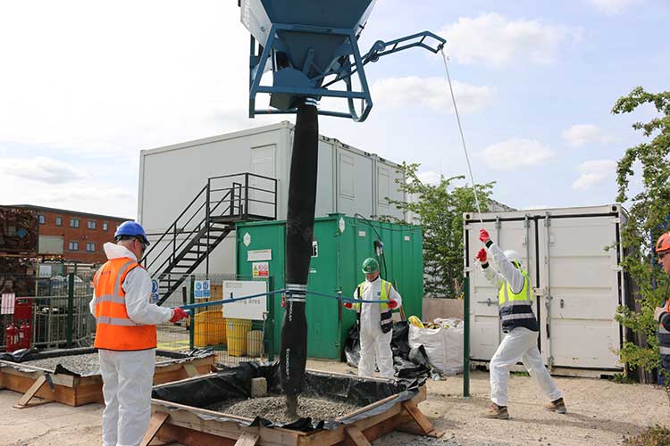 Three men pouring concrete with a concrete skip