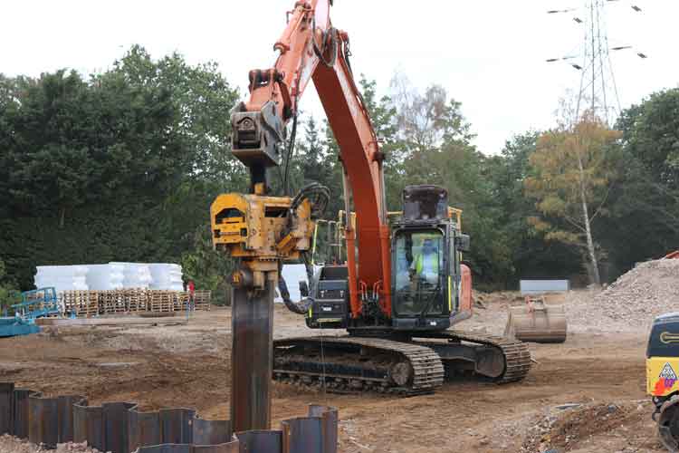 An excavator with an EV Hammer removing pile sheets in an construction site