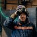 A man smiling and wearing a welders mask